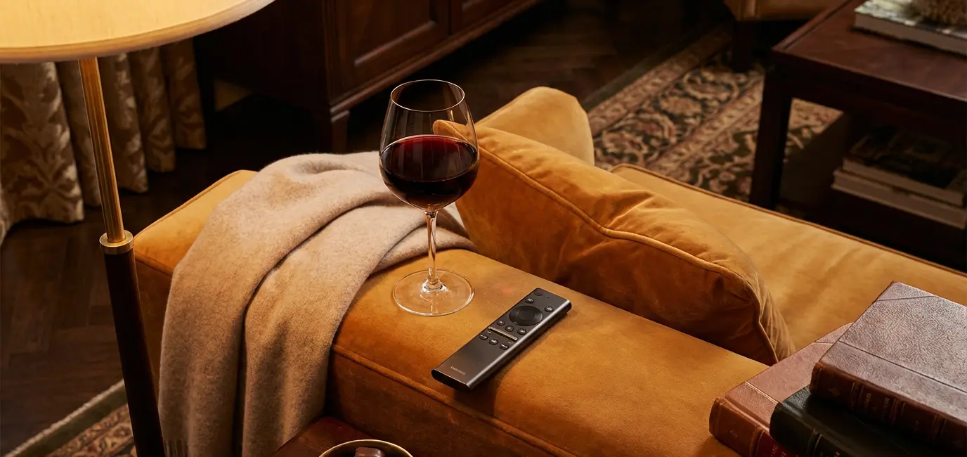 red wine glass next to TV remote on velvet couch for Bravo show viewing night