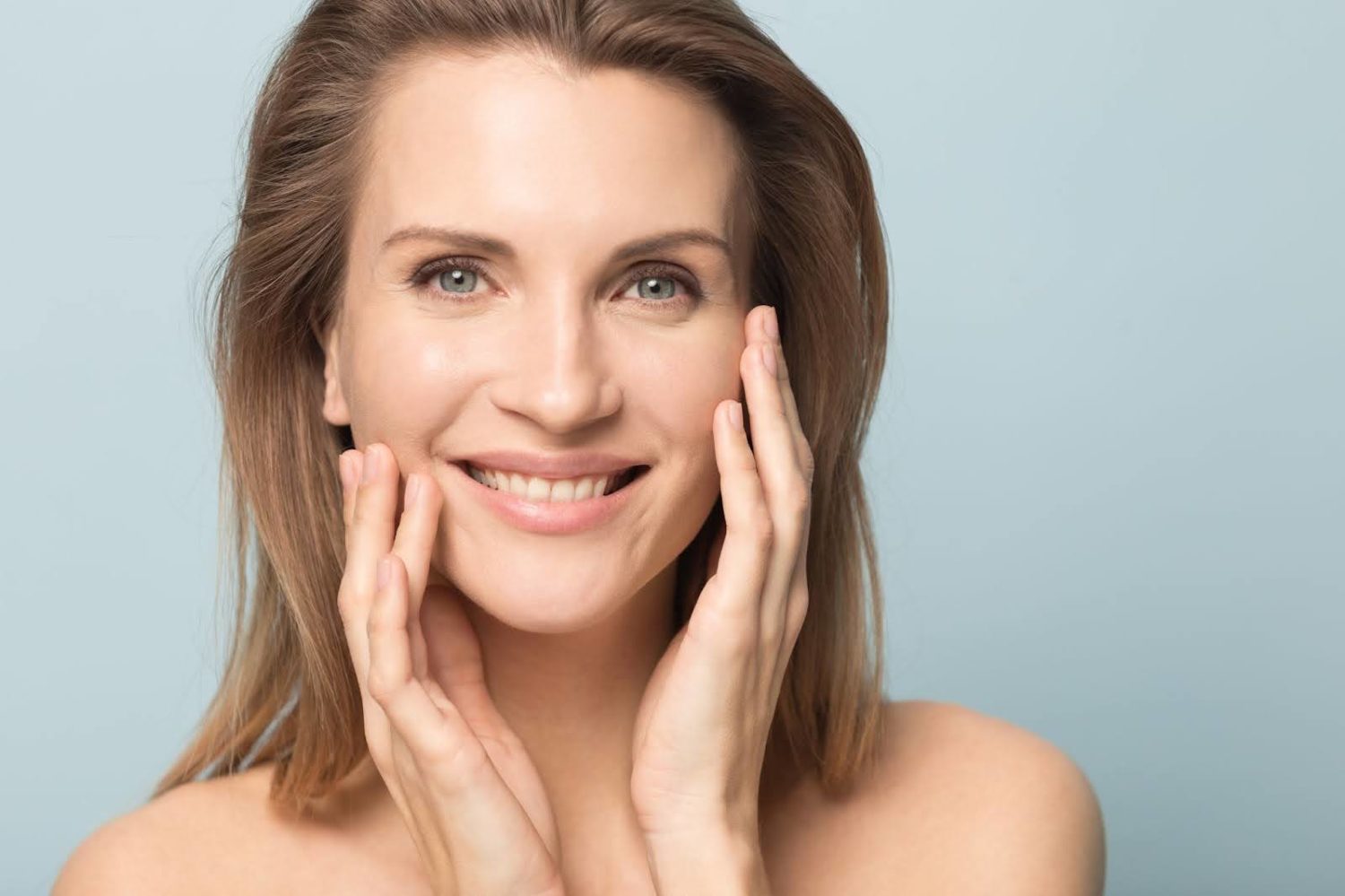 woman with smooth, youthful skin touching her face, highlighting the benefits of collagen supplements for reducing wrinkles and improving skin health.