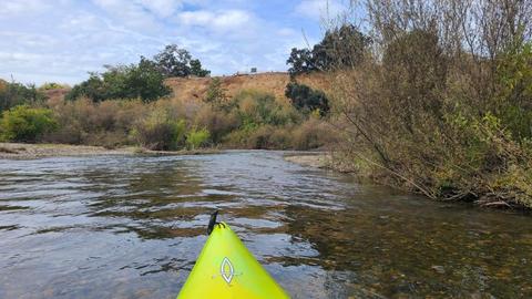 River mile 30.1, where the first riffle downstream from the Hickman Road bridge may be seen just ahead of the kayak. Directly over the kayak bow is the Tuolumne River Parkway parking lot and trailhead with its 135-step staircase. This location is 1.1 mile downstream from the beginning of this hotspot at the Hickman Road bridge.