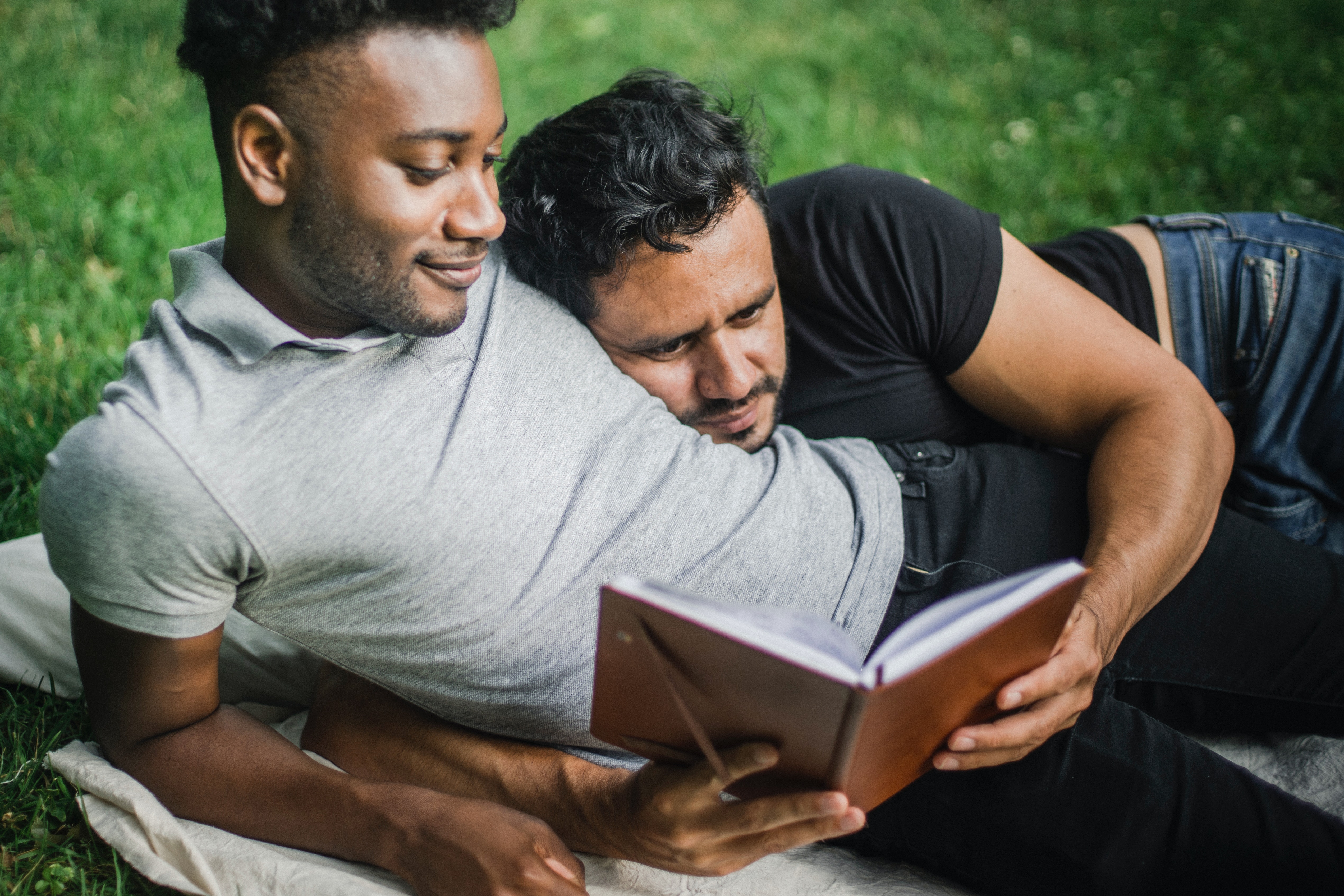 gay couple reading together outside