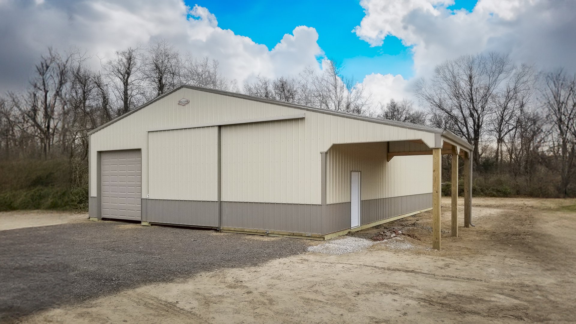 A light-colored post-frame building is shown with a gable roof and vertical siding. It features a large overhead garage door on the front, ideal for vehicle storage or a workshop. A smaller pedestrian door is present on the side, under a canopy supported