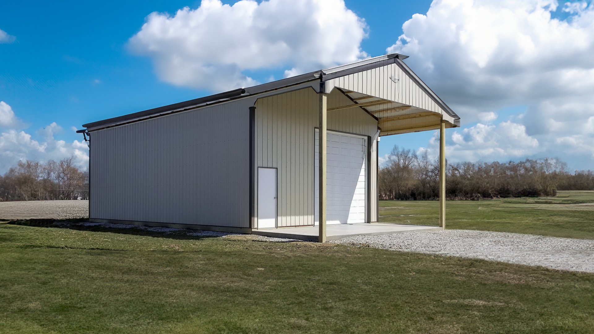 This image shows a post-frame building with beige metal siding and a gabled roof, featuring a large roll-up garage door at the front. The structure includes a small adjacent side door and an extended covered porch supported by two vertical posts. The buil