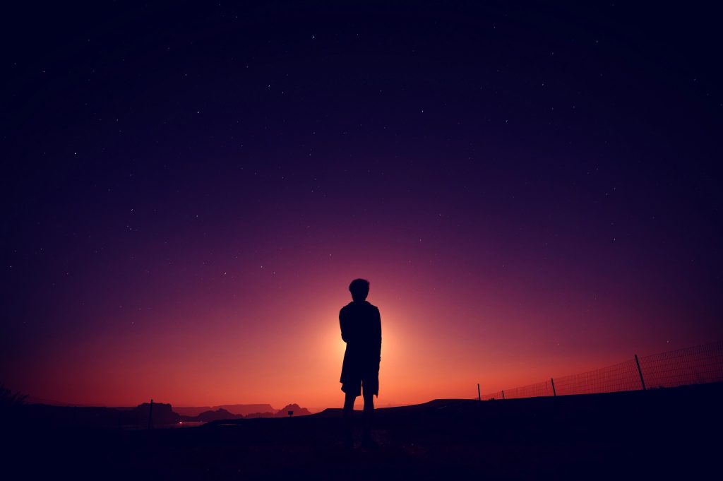 silhouette of boy standing at the end of dusk