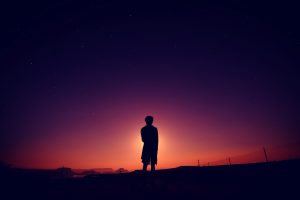 silhouette of boy standing at the end of dusk
