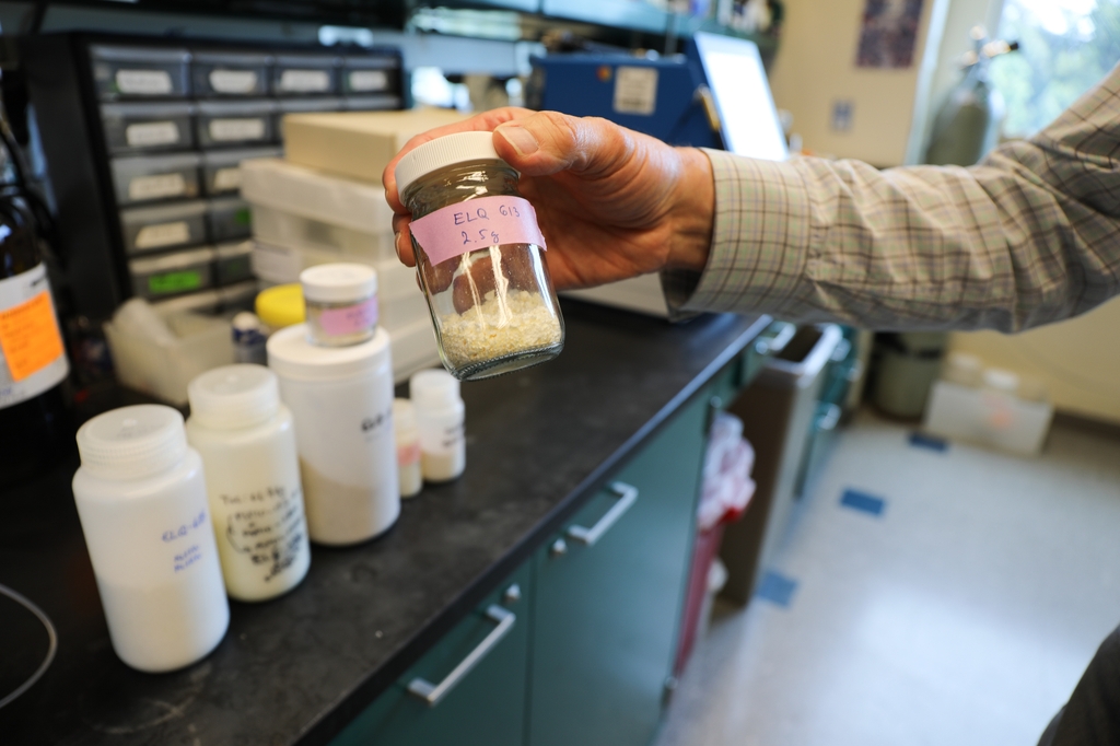 Photos shows Michael Riscoe, Ph.D., a professor in the Department of Molecular Biology and Immunology at Oregon Health & Science University, whose face is not shown just his arm and hand holding a jar filled with the compound he created in his lab. He is involved in a multi-institutional study published in Nature. The study demonstrates that combining drugs that kill the malaria-causing parasite with insecticide-treated bed nets can reduce infection rates.  (OHSU/Christine Torres Hicks)
