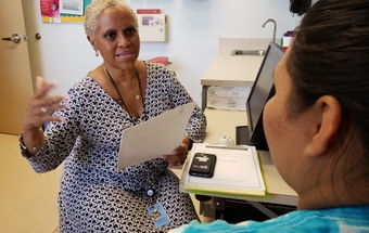 Milagros Amaro at the health department. Milagros Amaro works with a patient at the health department 2