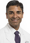 Dr. Navin Bhojwani smiles in a white lab coat.