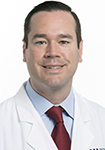 Dr. Andrew Marky is wearing a white lab coat and is smiling into the camera.