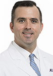 Dr. Robert Wiggins is wearing a white lab coat and is smiling into the camera.