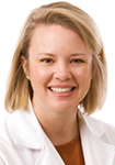 Dr. Kellie Schneider is wearing a white lab coat and smiles at the camera