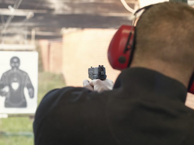 Shooting with a pistol. Man aiming pistol in shooting range.