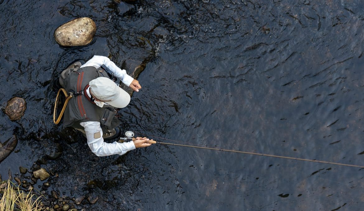 Fly fisherman using flyfishing rod in beautiful river