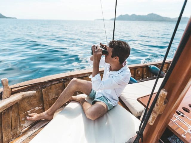 Man using binoculars on a sailboat