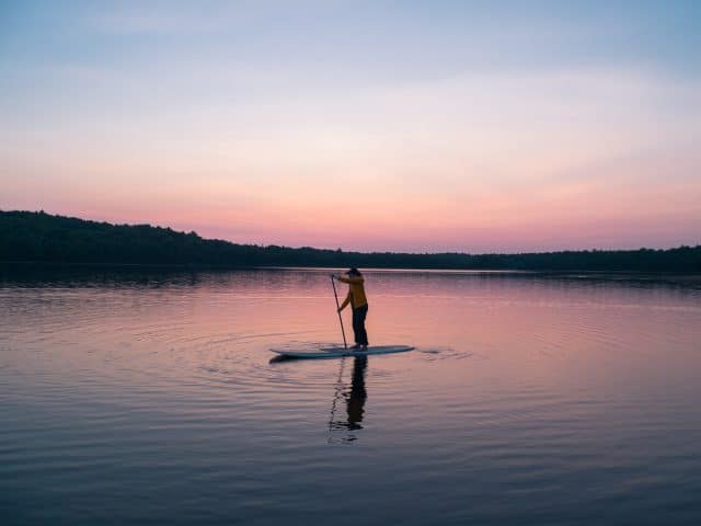 Paddleboarder on a lake at sunset