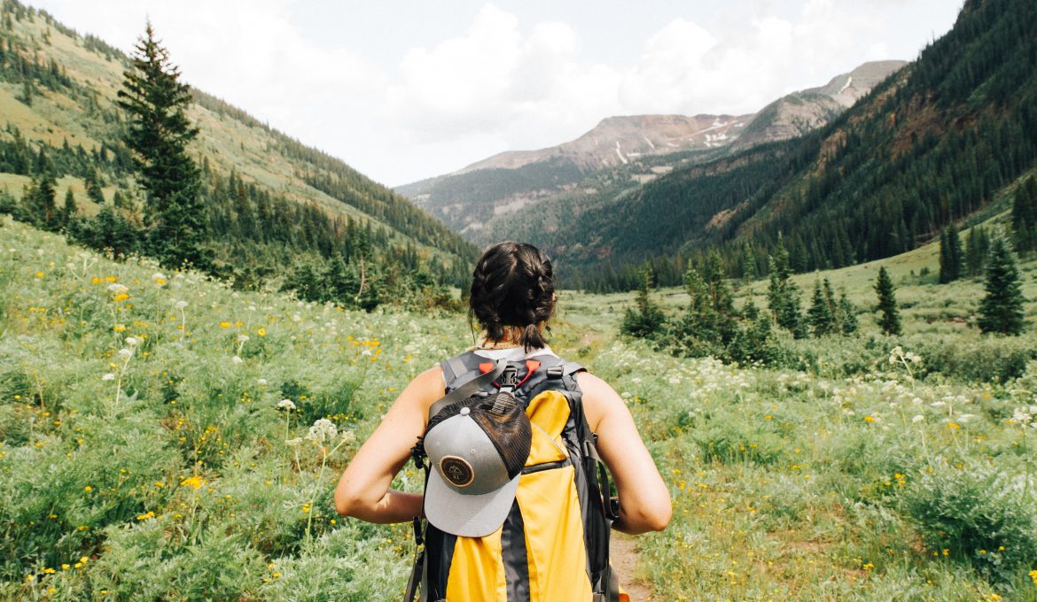 Woman hiking in grassy hills with yellow backpack