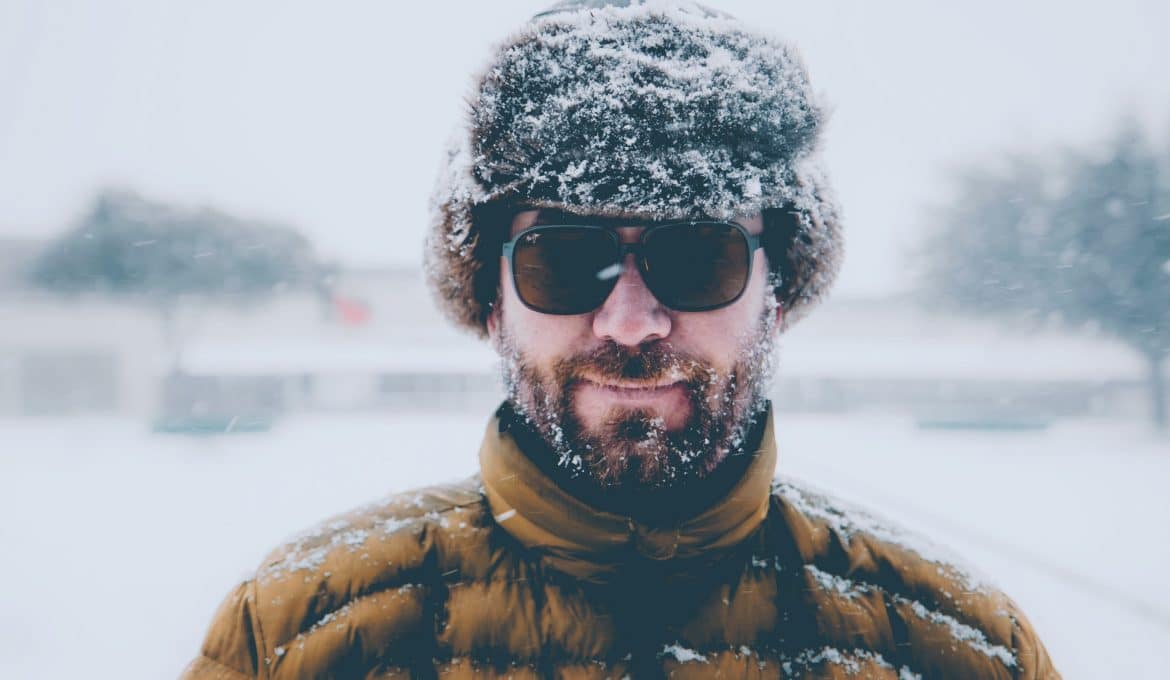 Man in furry hat with sunglasses in the snow