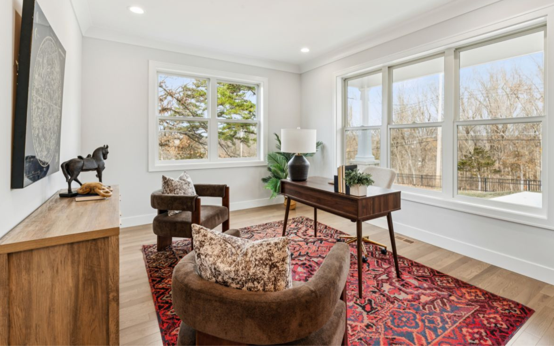 A bright, well-appointed home office with large windows and tree views in a St. Louis move-up home, representing the space and lifestyle that comes with buying up in the St. Louis real estate market.