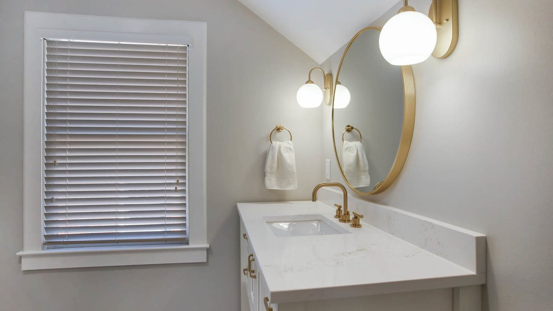 White bathroom remodel with vanity and round sconces