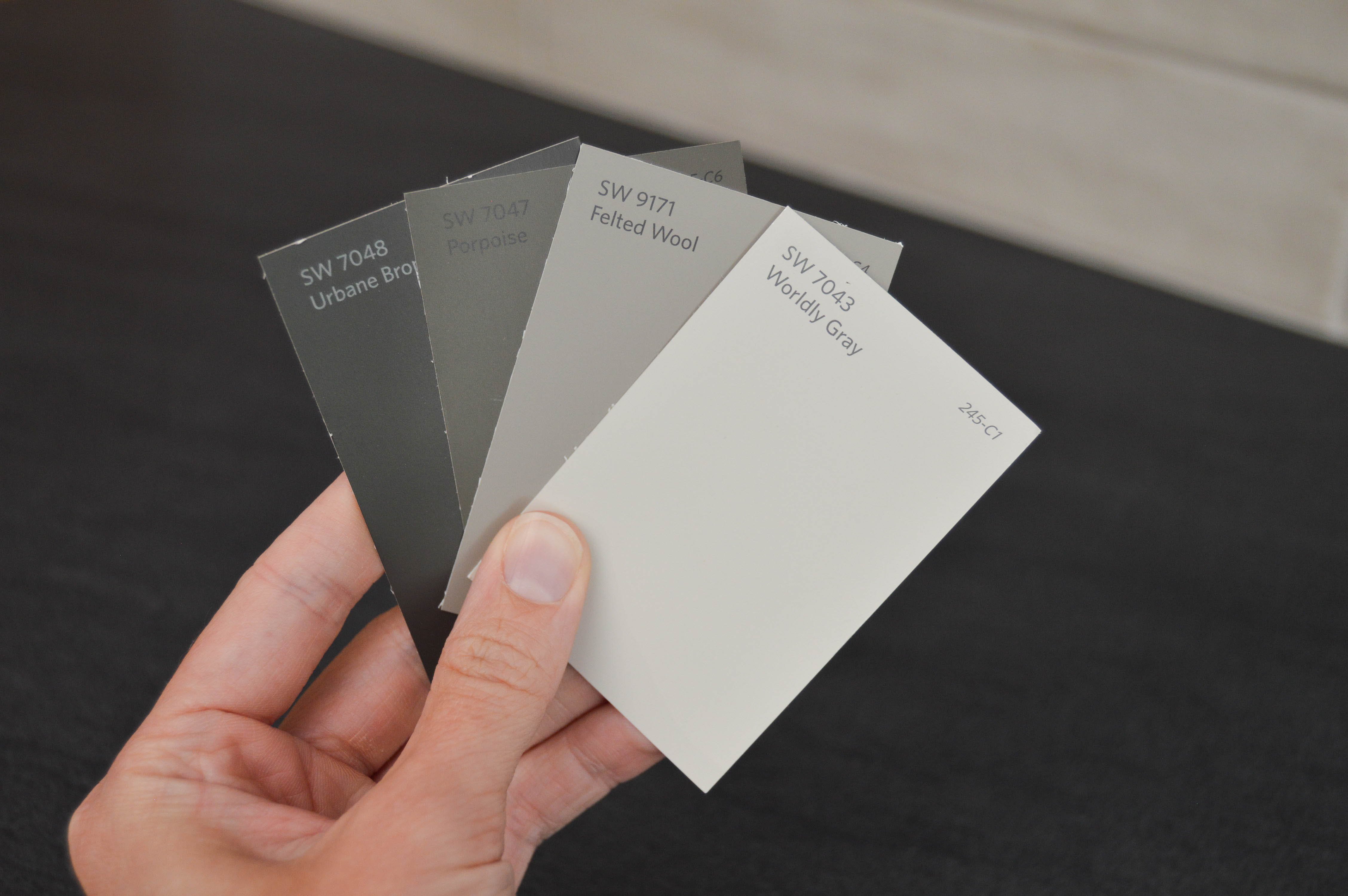 Hand holding various shades of gray paint swatches
