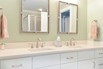 Green bathroom with double vanity and mirrors
