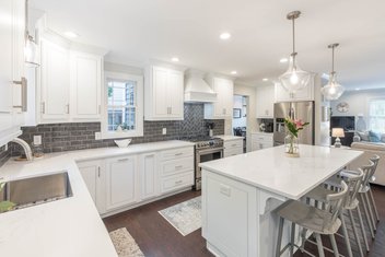 white kitchen with blue subway tile and kitchen island with four chairs at the bar