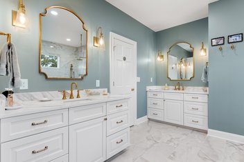 Blue bathroom with white cabinets and gold accents