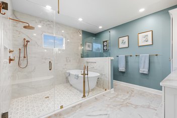 Luxury bathroom remodel with blue walls and tiled shower with tub