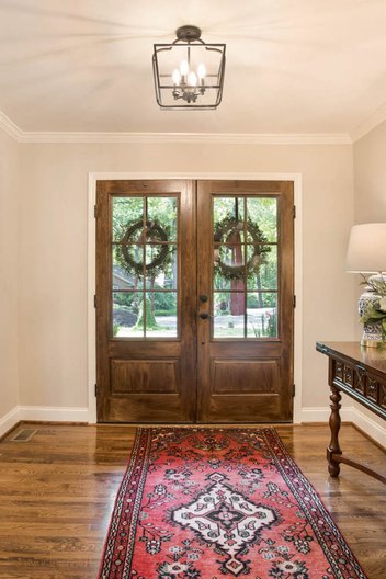 Entryway with wood doors, pendant light, wood floors and rug