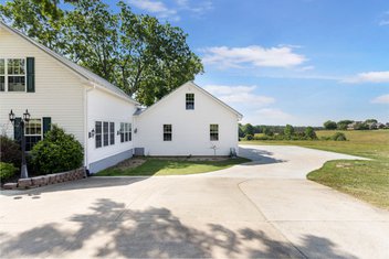 White garage addition off of white home in the country