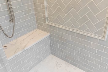 Gray subway tile shower with marble top bench