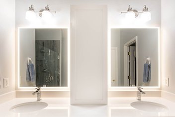 Bathroom with white double vanity with LED mirrors