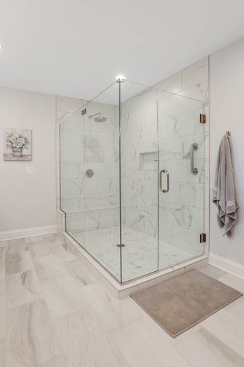 Neutral bathroom remodel with light grey walls, and large, tiled glass shower