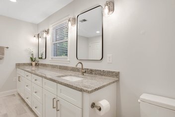 Neutral bathroom remodel with light grey walls, granite countertops and double vanity.
