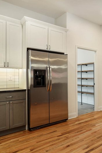 Simple white kitchen with stainless steel refrigerator