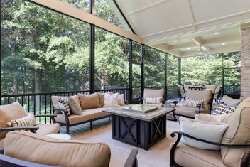 Interior view of screened porch on brick house with outdoor furniture