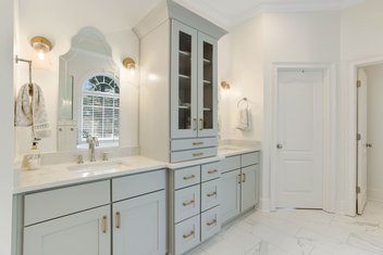Modern white bathroom with seafoam blue cabinets and Statuario tile floors