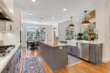 Remodeled kitchen with new cabinetry, quartz countertops, refinished floors, and custom hood