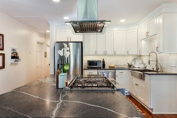 Modern kitchen with white cabinets and black via lattea granite countertops