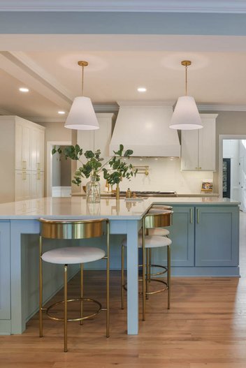 white kitchen with blue cabinets, white counters & pendant lights over island