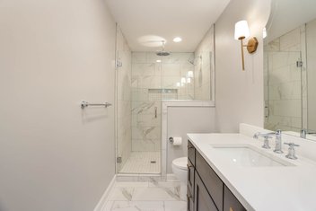 White bathroom with tiled shower and navy cabinets