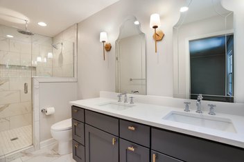 Simple white bathroom with navy cabients and white countertops