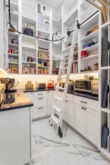 Walk-in pantry with white shelves and ladder that slides around