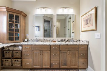 Neutral bathroom with double vanities natural wood cabinets and Blue Flowers Granite countertop