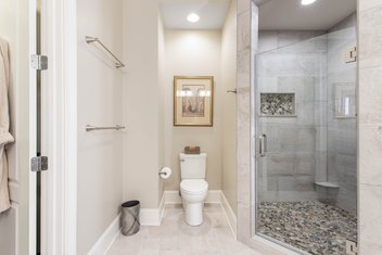 Neutral bathroom with toilet and tiled shower with glass door