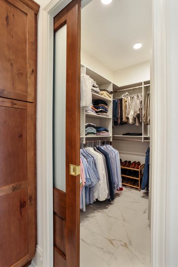 Brown pocket door between bathroom and closet with clothes