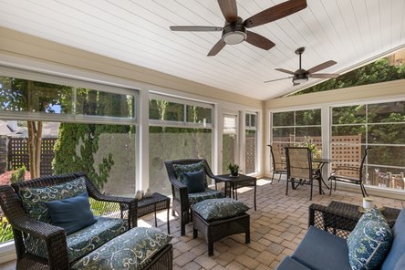 Screened porch with open windows looking into a small green backyard