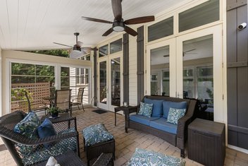 Screened porch with patio furniture, white ceiling, and modern fans