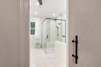 White barn door partially open looking into bathroom with glass shower
