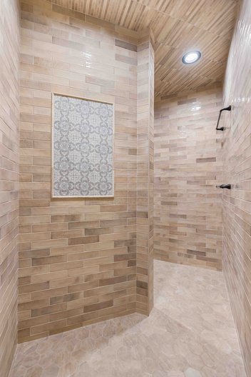 Tan tiled shower with tile mosaic accent