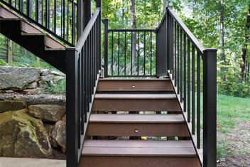 Brown deck stairs with lighting and black railings